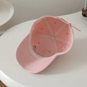 Detail of pink cotton baseball cap interior showing six-panel stitching and bear embroidery