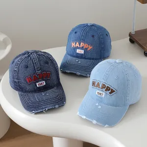 Détails de casquettes en jean délavé avec broderie Happy et finitions bords usés