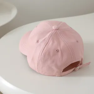 Detailed view of pink cotton baseball cap featuring back metal buckle and vent holes