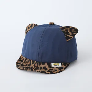 Close-up of baby baseball cap with leopard print ears and navy blue cotton fabric