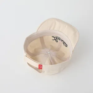 Detail view of cotton baby baseball cap interior with adjustable strap and red brand tag