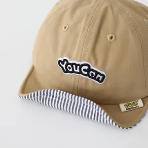 Detail of beige baby baseball cap with soft brim and black YouCan letter embroidery
