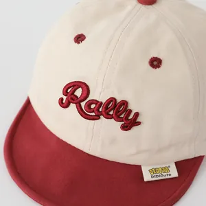Gros plan sur la broderie RALLY et le bord souple de la casquette bébé en coton