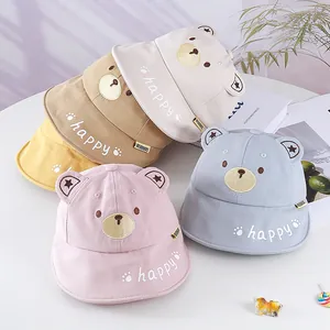 Detail of colorful baby bucket hats with bear ears and happy embroidery on white table