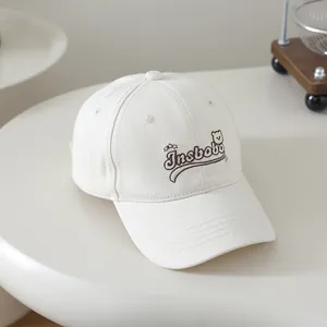 Detail of embroidered cartoon bear and Insbobo lettering on cream cotton baseball cap