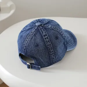 Détail d'une casquette de baseball en jean délavé avec texture usée et boucle en métal