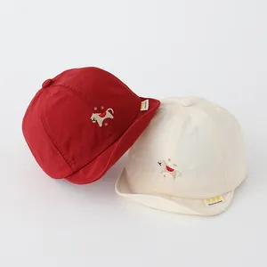 Detailansicht der Baby-Soft-Baseballkappen mit Comic-Stickerei in Rot und Beige