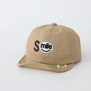 Close-up of smile embroidery and brand tag on khaki soft cotton toddler baseball cap