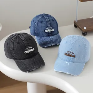 Détail de casquettes en jean délavé avec broderie et visière aux finitions usées