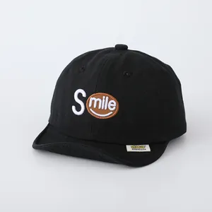 Detail of black cotton baseball cap showing SMILE embroidery and a soft short brim