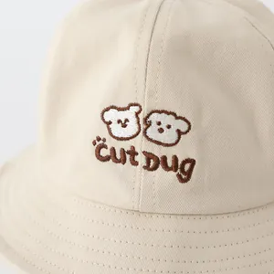 Dettaglio ravvicinato del cappello da sole in cotone beige con ricamo animale e testo Cut Dug