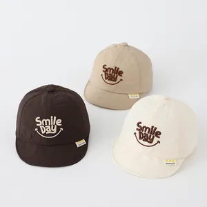 Three colors of soft brim baby baseball caps with Smile Day embroidery on white background