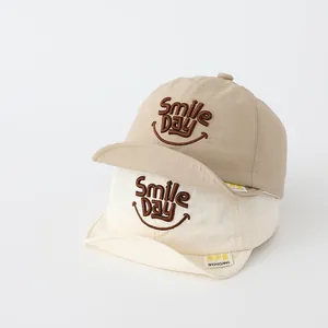 Detail of baby soft brim baseball hats with Smile Day embroidery in beige and cream