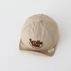 Detailed embroidery of Smile DAY text and smiley face on a soft beige baby baseball cap
