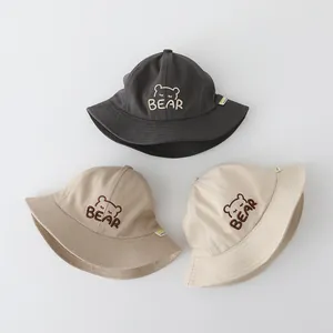 Dettaglio di tre cappelli pescatore in cotone grigio, kaki e beige con orsetto ricamato