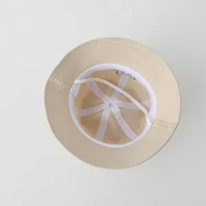 Dettaglio dell'interno di un cappello da pescatore beige per bambini con cordino e ricami