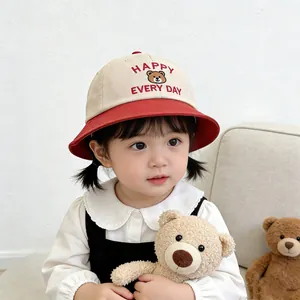 Detail of baby sun hat featuring Happy bear embroidery and red contrast brim design