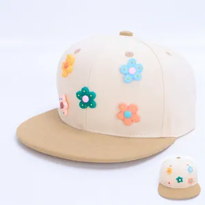 Detalle de flores 3D coloridas en una gorra snapback beige y marrón para niños