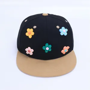 Detalle de cinco flores 3D de silicona en una gorra de béisbol negra para niños