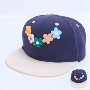 Detalle de gorra infantil con visera contrastada y cinco flores 3D de colores decorativas