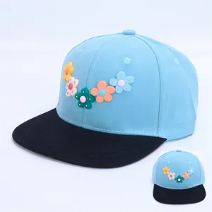 Detalle de gorra infantil azul cielo con cinco flores 3D coloridas y visera plana negra