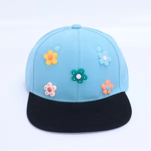 Detalle de gorra infantil azul con cinco flores en 3D de colores y visera plana negra