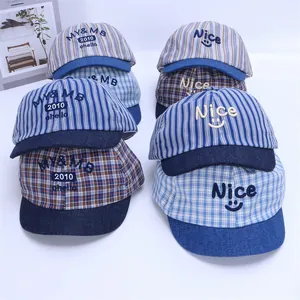 Flat lay of six striped and plaid baby baseball caps with smiley face embroidery