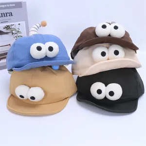 Detail view of cotton baseball caps with cartoon big eyes in blue, yellow, and brown