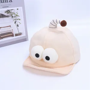 Close-up of cream baby baseball cap with plush cartoon eyes and striped antenna detail