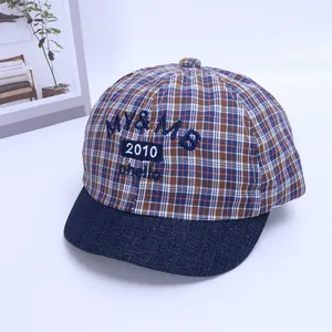 Detail of plaid cotton baseball cap featuring blue embroidery and denim soft brim