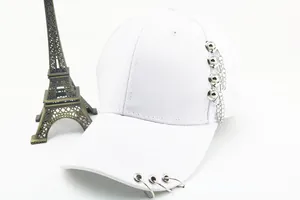 Détail d'une casquette en coton blanc avec anneaux métalliques et chaîne argentée
