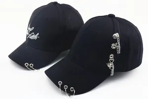 Détail de casquettes en coton noir avec anneaux métalliques, chaînes et broderies