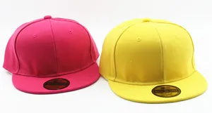 Detail of hot pink and yellow cotton twill baseball caps with logo stickers on brim