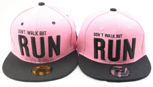 Détail de la casquette snapback rose avec broderie RUN noire et autocollant doré