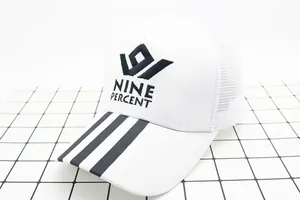 Close-up of white mesh trucker hat with NINE PERCENT embroidery and black brim stripes