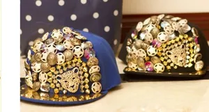 Detail of baseball caps with gold leopard head, metallic studs, and star decorations