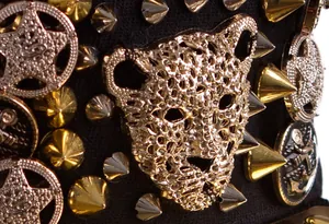 Detail of metal leopard head and spiked rivets on punk style black baseball cap