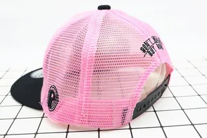 Detail of pink and black trucker hat featuring breathable mesh and adjustable snap closure