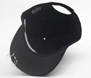 Internal view of black cotton baseball cap showing metal rings and white paper inner mold