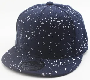 Detail view of a navy blue snapback cap with white paint splatter and sport sticker