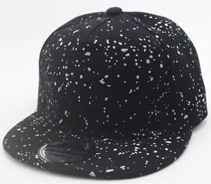 Detail of black snapback hat with silver ink splatter pattern and flat brim sticker