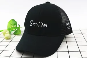 Detailansicht der weißen Smile-Stickerei und des Mesh-Gewebes der schwarzen Kindermütze