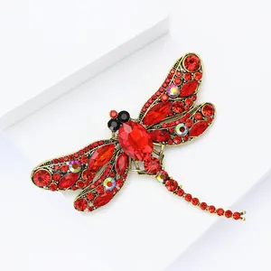 Close-up of vintage gold dragonfly brooch with red gemstones and sparkling rhinestones