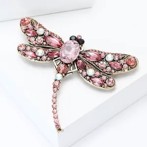 Detailed close-up of dragonfly brooch with pink crystals and rhinestones on gold base