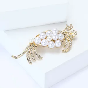 Close-up detail of rhinestone leaf and pearl cluster on an elegant gold brooch