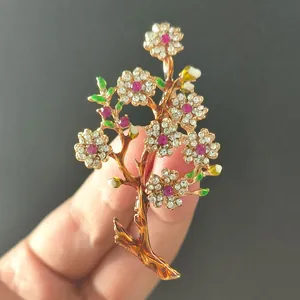 Detailed macro view of crystal-encrusted flower brooch with gold plating and green enamel