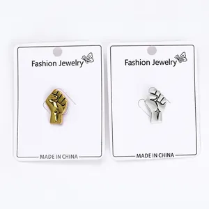 Detail of metal power fist brooches in gold and silver finish on display cards