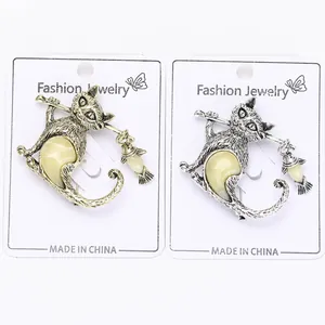 Detailed view of vintage gold and silver cat brooches with amber resin and fish charms