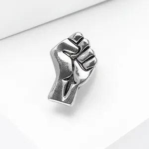 Detailed view of a silver-colored clenched fist brooch with metallic finish and black accents