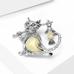 Detail of vintage silver cat and fish brooch with yellow synthetic opal inlay